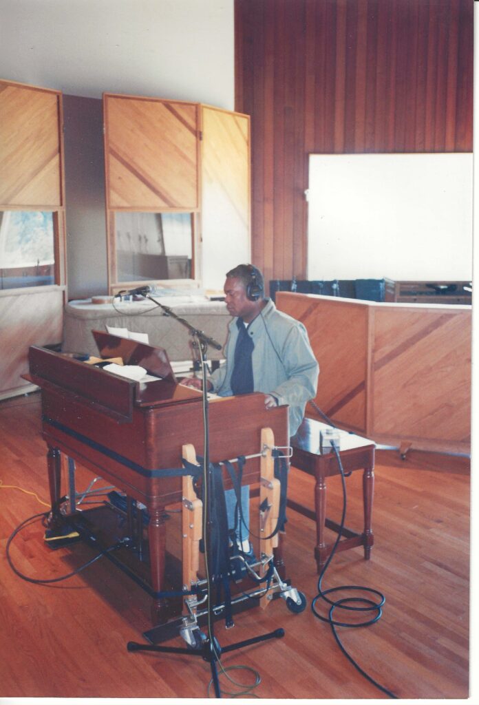 A musician performing at an organ inside a professional recording studio.